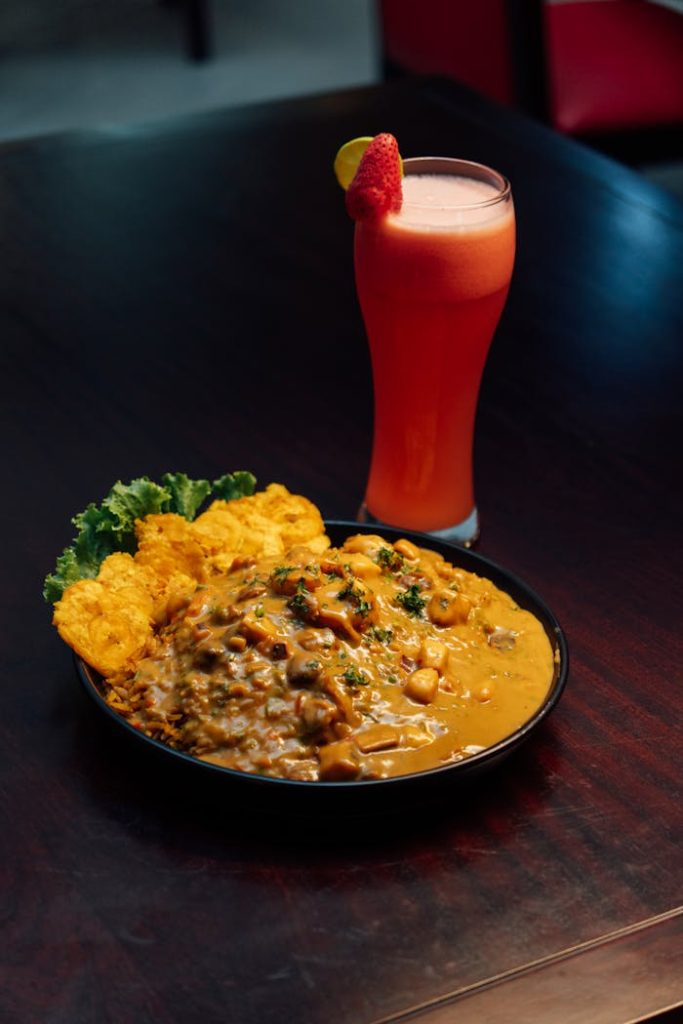 Authentic Caribbean dish with plantains and a vibrant fruit drink, perfect for food lovers.